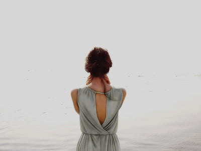 photo of woman facing body of water wearing gray top