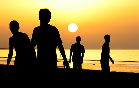 Silhouette of 4 People Near Ocean during Sunset