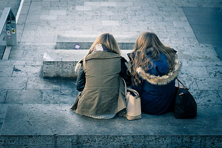 two women sitting on gray concrete bench