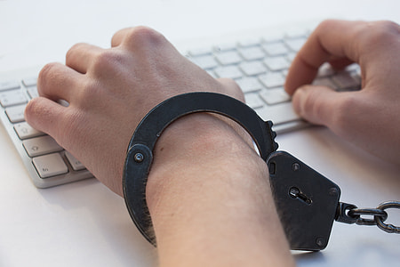 person with handcuffs typing on the white keyboard