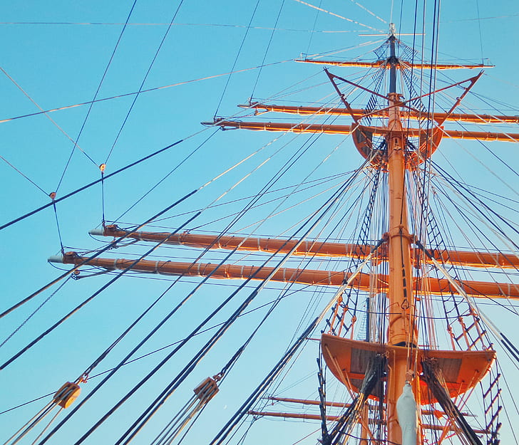 low-angle photo of orange wooden ship mast during daytime