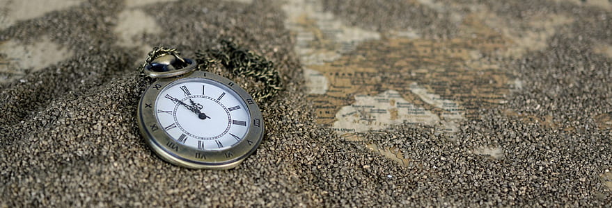 round silver-colored pocket watch on brown sands