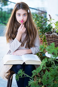 girl wearing white sweater with book opened on her lamp