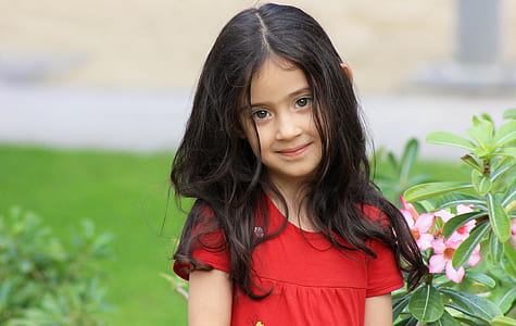 girl wearing red scoop-neck short-sleeved top near flower during daytime