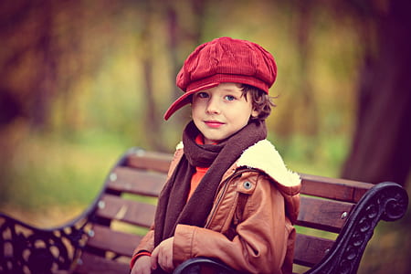 boy wearing red corduroy newsboy cap and brown parka coat