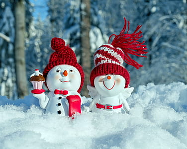 two white-and-red snowman figurines standing on snow field