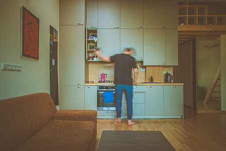 photo of man in front of kitchen cabinet opening one door of cabinet