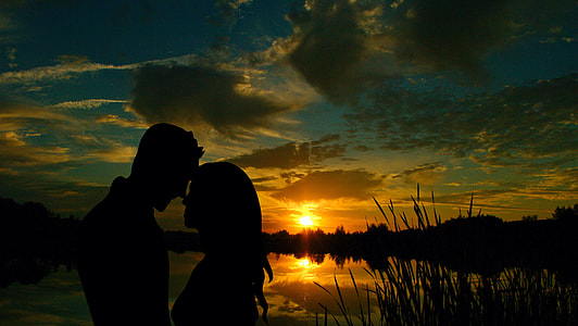silhouette photography of man and woman beside body of water