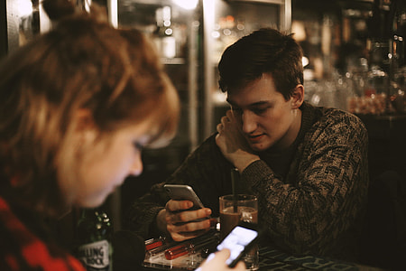 man and woman inside the restaurant holding smartphones