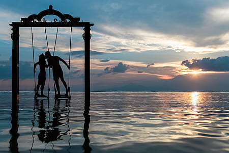 man and woman on swing kissing on ocean