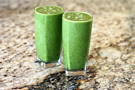 two clear glass cup full of green smoothie