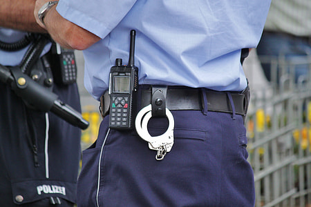 person in blue uniform with gray handcuffs