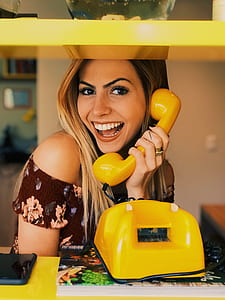 photo of woman holding yellow telephone