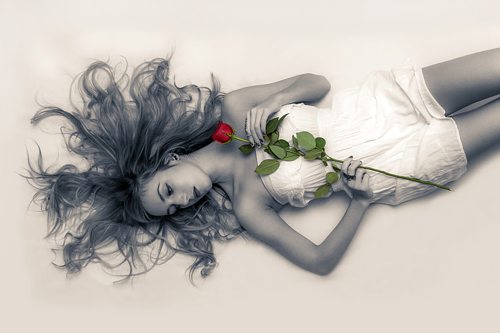 selective color photography of woman holding red rose