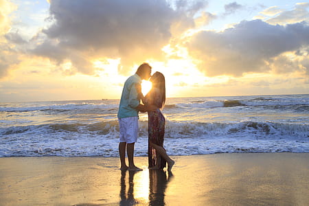 man and woman kissing near wavy sea