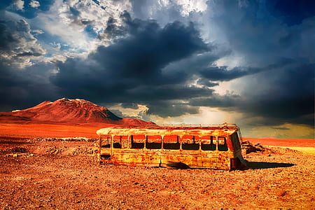 photography of brown bus frame next to brown mountain during daytime