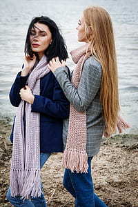two women wearing scarves standing near body of water