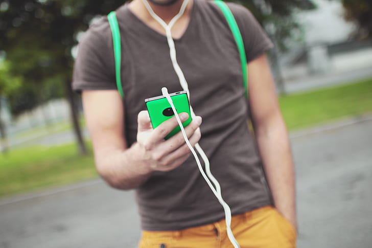 selective focus photography of man holding green smartphone