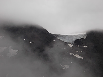 black mountain filled with snow and fog