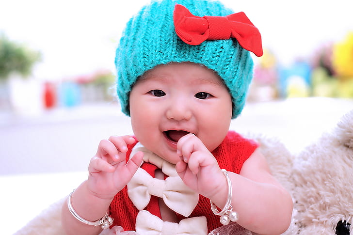 baby wearing red top and blue knit cap