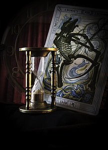 closeup photo of hour glass and tarot card