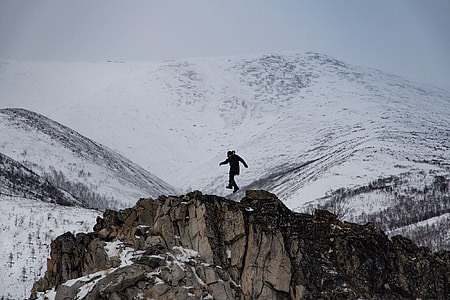 man on top of brown mountain near white mountains during daytime
