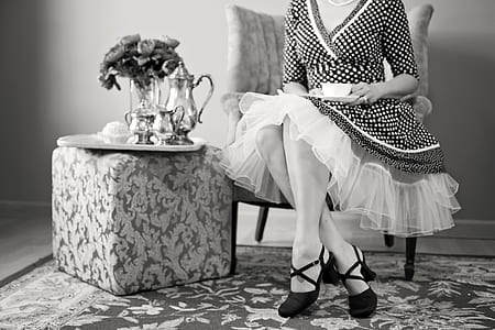 grayscale picture of woman sitting next to end table