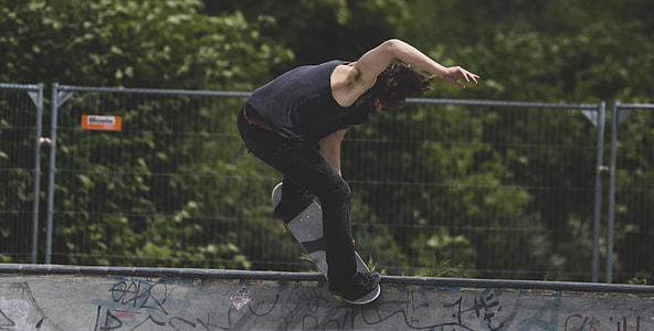 man in black tank top and pants playing skateboard