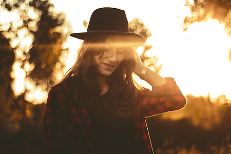 woman wearing red and black checkered dress shirt and black hat during sunrise
