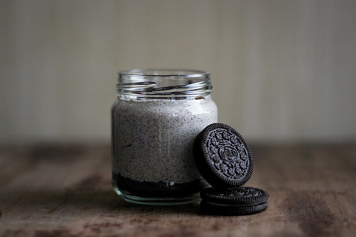 shallow focus photography of two chocolate biscuits leaning on clear glass bottle