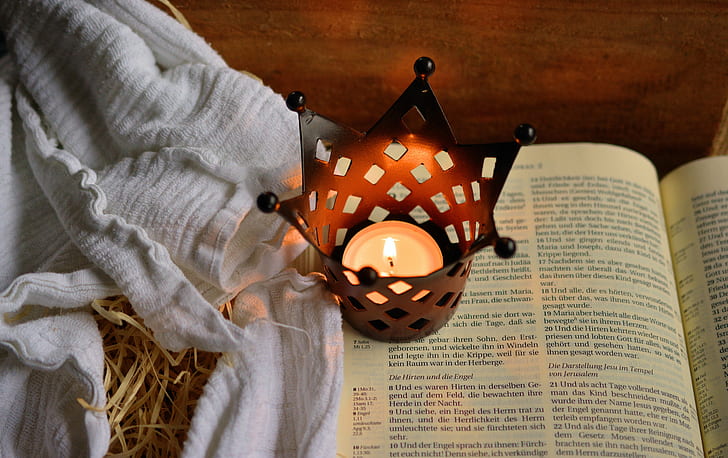 photo of tealight candle in crown candle holder on open book