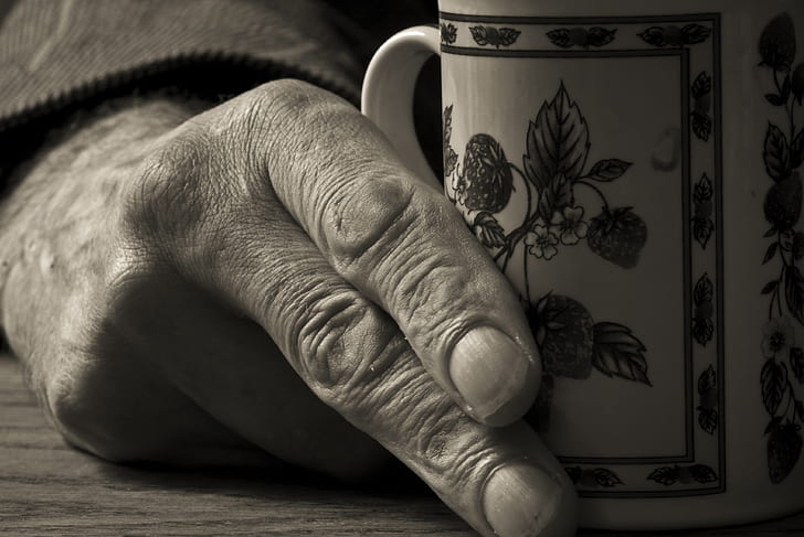 grayscale photo of person holding mug