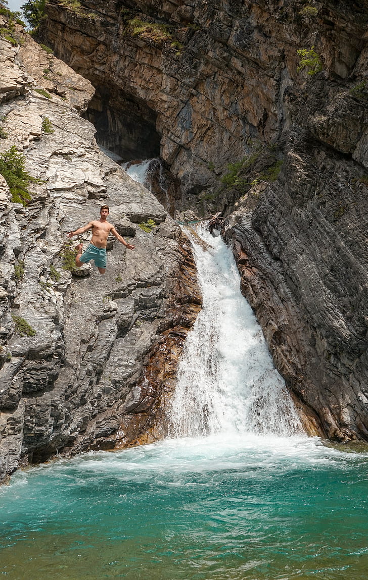 man wearing blue shorts jumped on waterfalls