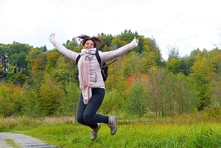 woman wearing jacket and blue denim jeans jumping