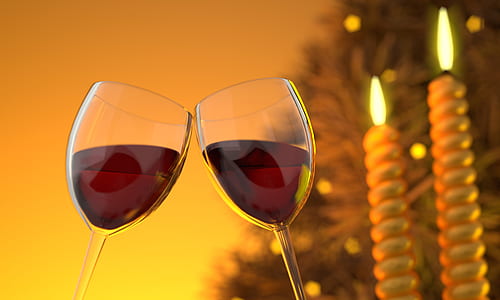 two clear wine glasses with red liquids near two white candle sticks in tilt shift photography