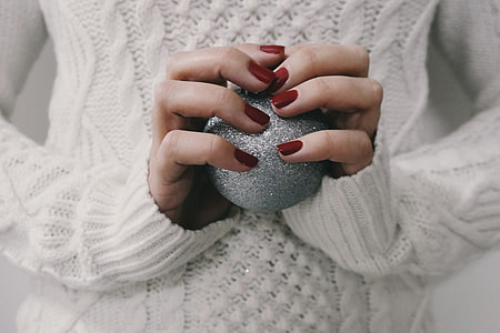 Closeup shot of a woman’s hands holding a silver Christmas decoration ball