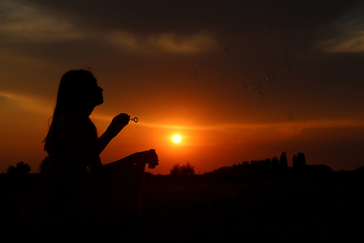 silhouette photo of a woman holding bubble making stick