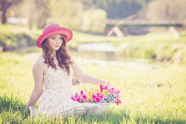photo of a woman sitting on ground holding bouquet of basket flower