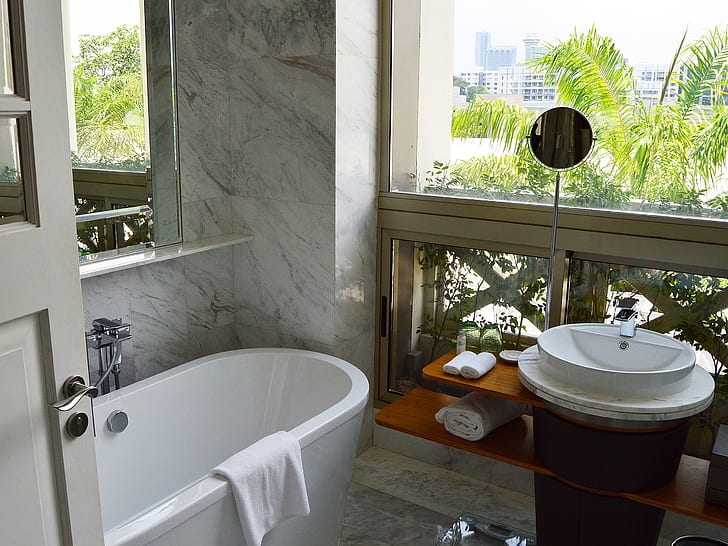 bath tub near glass window and vanity sink