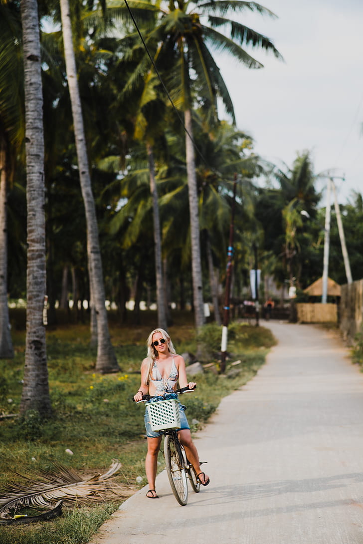 woman riding a bicycle beside green coconut trees
