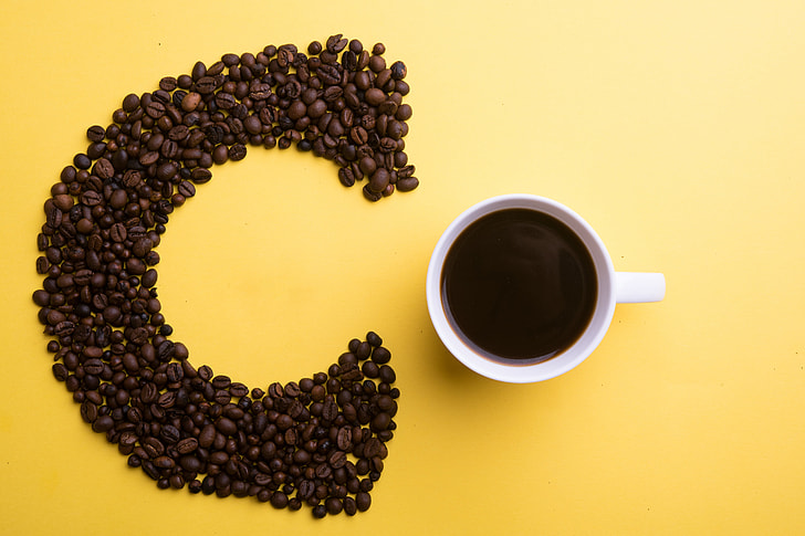 Coffee beans and cup on yellow background