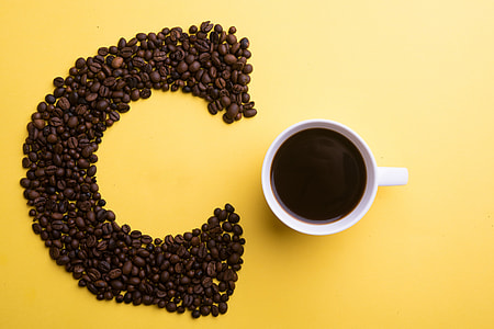 Coffee beans and cup on yellow background