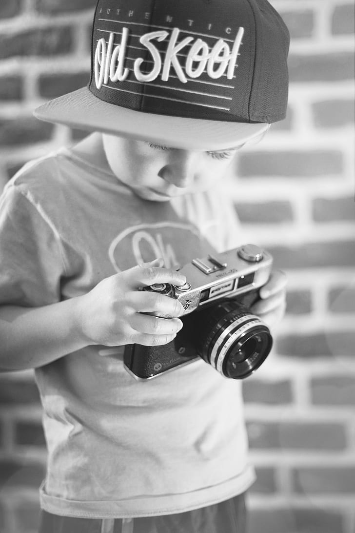 grayscale photo of boy holding rangefinder camera