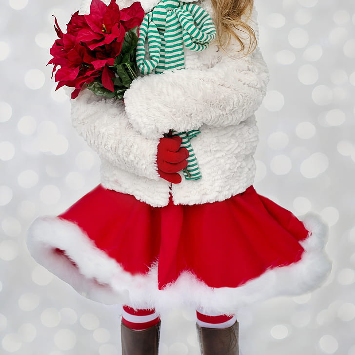 girl in white knit jacket and red mini skirt holding red poinsettia bouquet