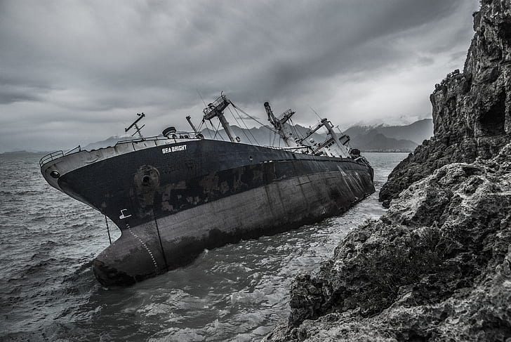 grayscale photo of black ship near shoreline