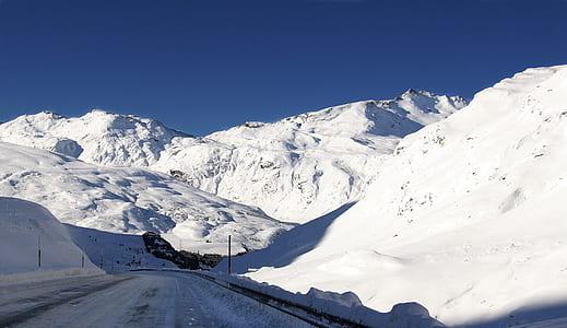 snow covered concrete road between snow covered mountains at daytime