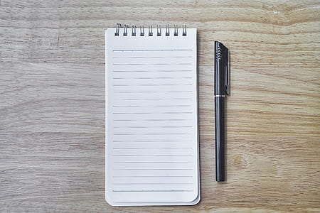 closeup photo of notebook and ballpoint pen