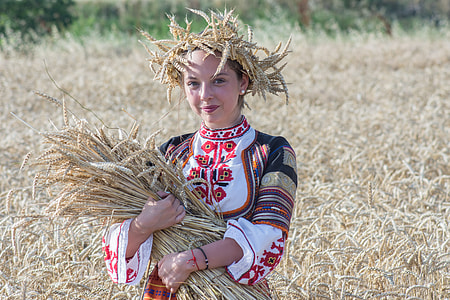 woman wearing white and red long-sleeved dress holding bunch of wheat barley