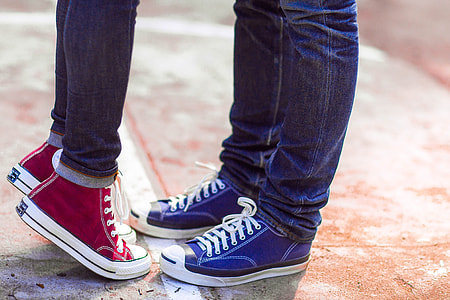 two person wearing blue denim jeans, blue and red high-top sneakers standing