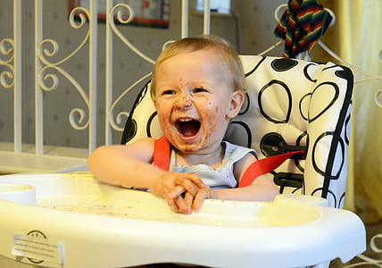 baby wearing white sleeveless top sitting on high chair